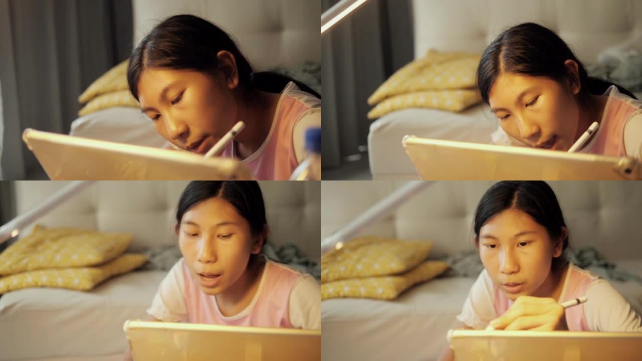 亚洲女孩用数字平板电脑和铅笔在家里窗户附近的日本折叠桌上做作业，生活方式理念。