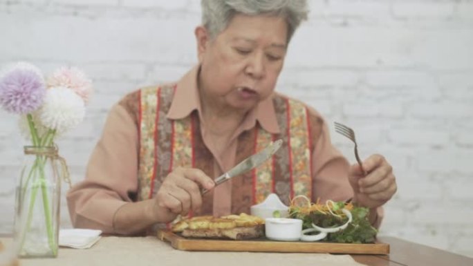 老年老年妇女吃烤猪排牛排食物。成熟的退休生活方式