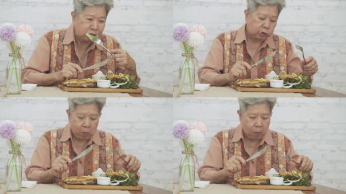 老年老年妇女吃烤猪排牛排食物。成熟的退休生活方式