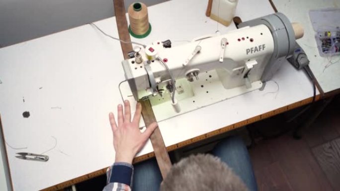 在缝纫机上工作的无法识别的高加索裁缝的高角度视图