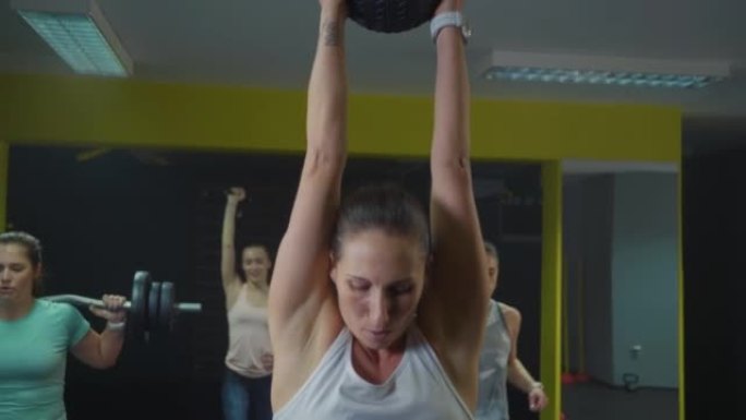 女人在健身房做举重球大满贯练习，手持射击