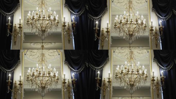 丰富的水晶吊灯反射在镜子里。烛台挂在墙上。