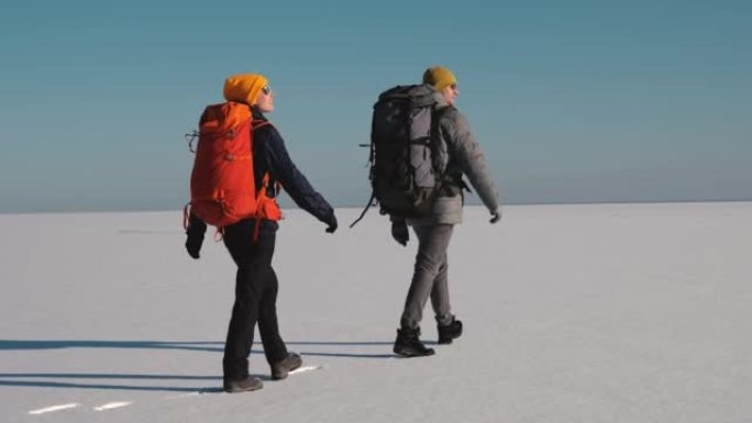 两个背着背包的旅行者徒步穿越雪场。慢动作