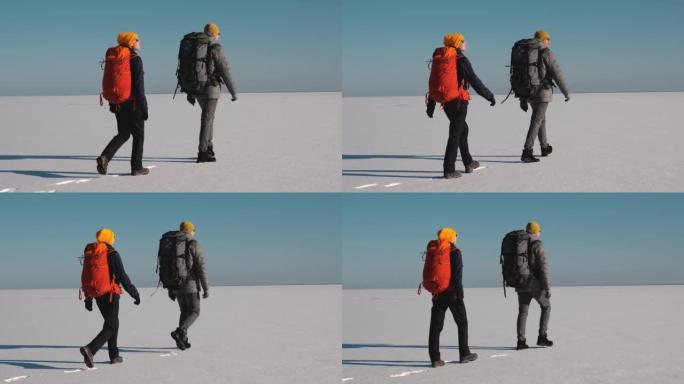 两个背着背包的旅行者徒步穿越雪场。慢动作