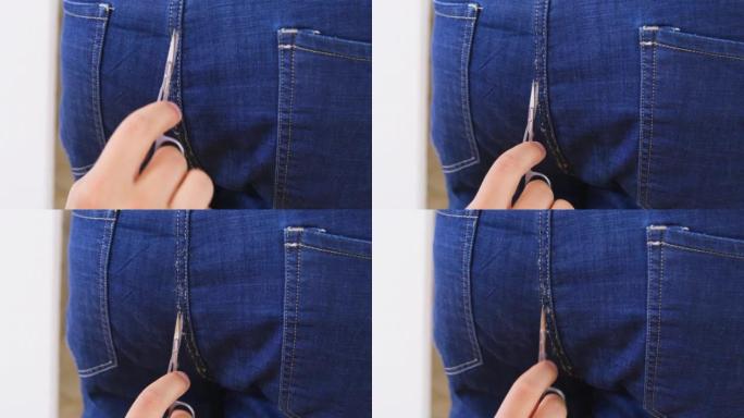 用指甲剪的手剪掉了一个人穿的牛仔裤上接缝处的突出线。