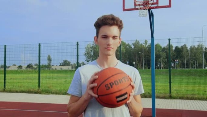运动员的肖像，一个在运动场上的家伙，手里拿着篮球，看着相机