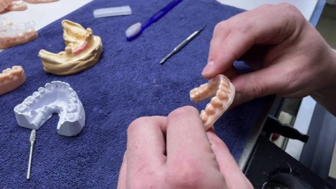 假牙。专业技术人员使用工具切割人造牙齿模型牙齿。工具切割假牙模型。牙科修复体的生产。人造牙齿模型。4