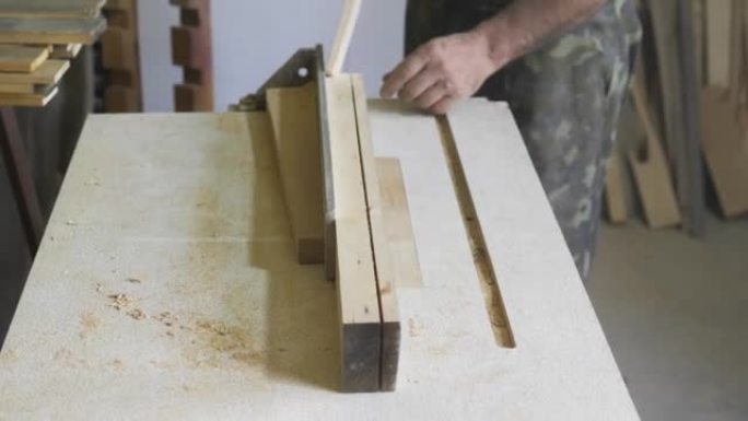 特写: 他车间里的一个木匠用圆锯锯一块木板，在自然光下制作家具零件。木匠用木头工作。家庭修理的建筑工