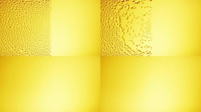 水滴从黄色bg上的湿玻璃的一半上吹下来