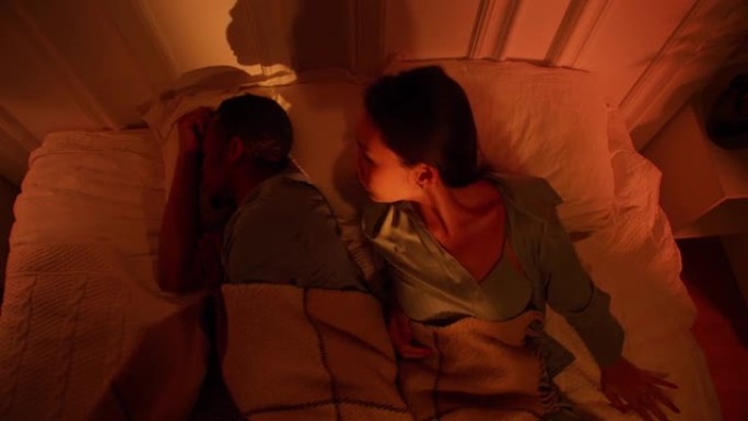亚洲妇女和黑人男子正试图在嘈杂的公寓里打呼噜入睡