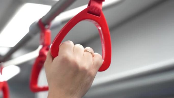 城市公共交通中男性手持环形把手的特写视图。上班时在火车上握着把手的人。