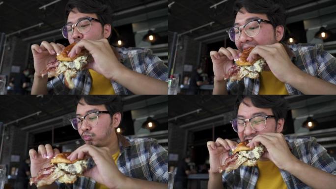 年轻人的特写镜头，用凌乱的手和嘴咀嚼一口芝士汉堡。