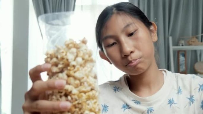 女孩用塑料袋包装爆米花，通过数字平板电脑在线销售，在家中的小企业概念。女孩在周末为自己赚钱而学习。