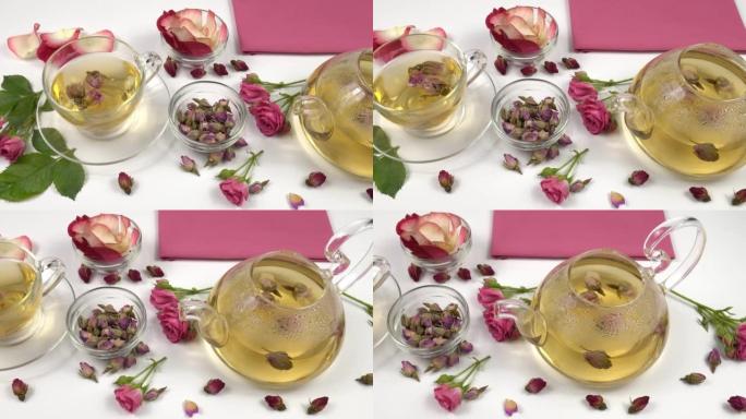 茶壶和杯子，配以新鲜的粉红玫瑰中的粉红玫瑰花蕾花茶