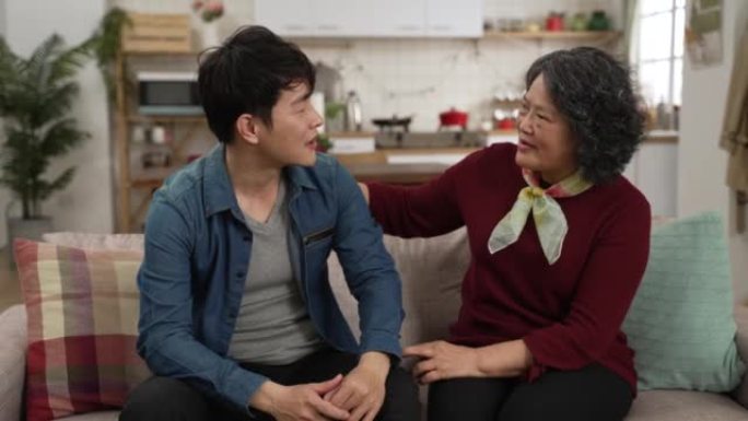 有爱心的亚洲奶奶鼓励她成年的孙子，并对他在家中的生意表示最良好的祝愿。男人微笑着拥抱老妇，握紧拳头