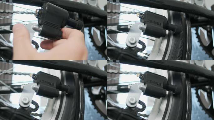 男人的手打开自行车发电机。将自行车发电机靠近轮胎。特写，踏板运动，室内。