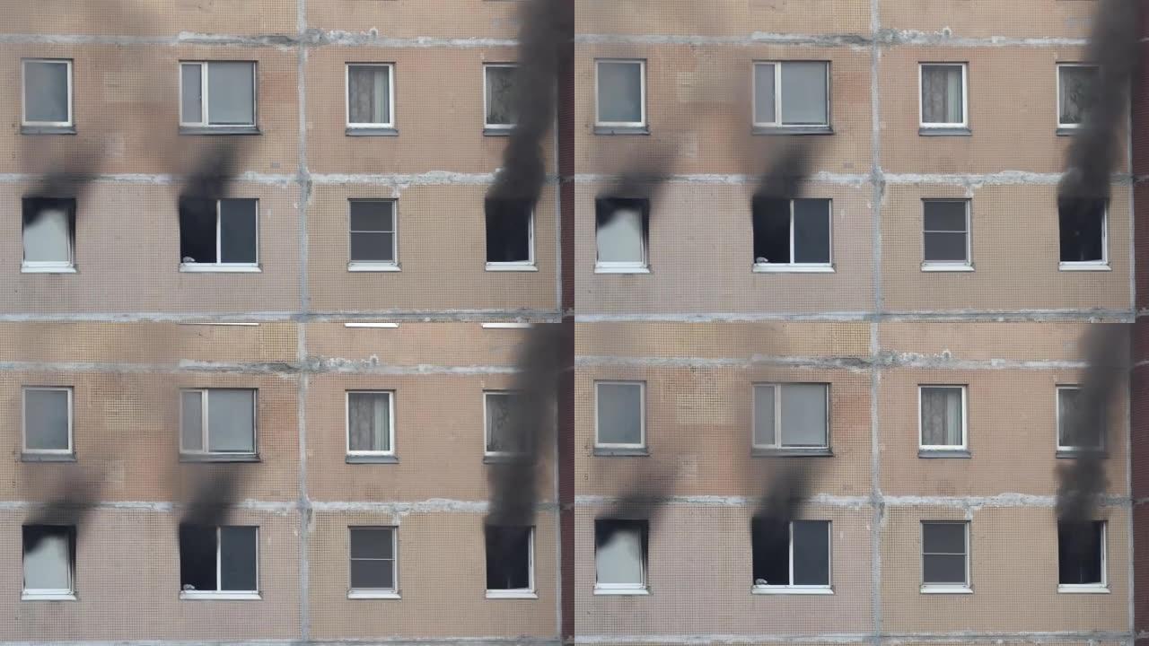 一栋公寓楼的三扇窗户冒出黑烟。公寓里着火了。