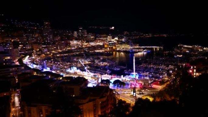摩纳哥赫尔库勒港的空中夜景，法国里维埃拉系泊游艇，配有照明游乐场和建筑。