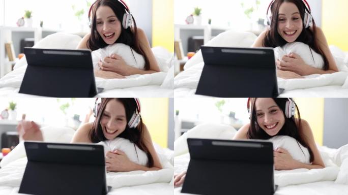 戴着耳机微笑的幸福女人躺在床上通过视频通话进行交流