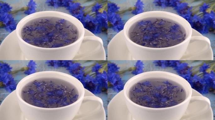 复古浅蓝色木制桌面上有白色和蓝色的花。用白色杯中的花花酿造tisanes。