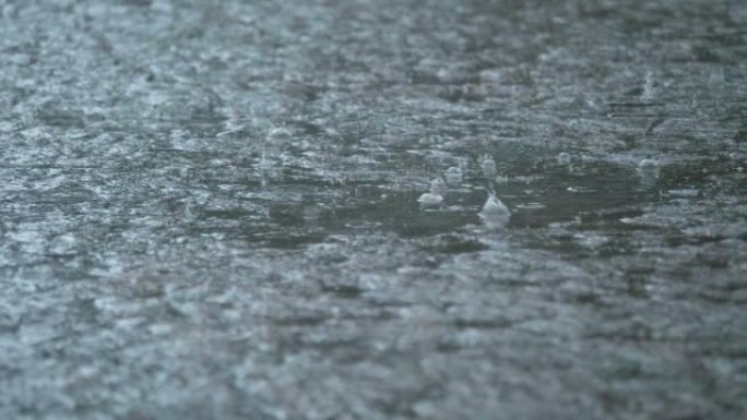 多雨的天气，水滴掉落并在水坑中缓慢运动。