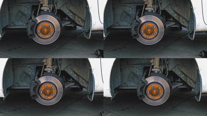 汽车轮毂，在车库车间轮胎更换过程中暴露出制动盘和制动片，凸耳螺母铺在地面上