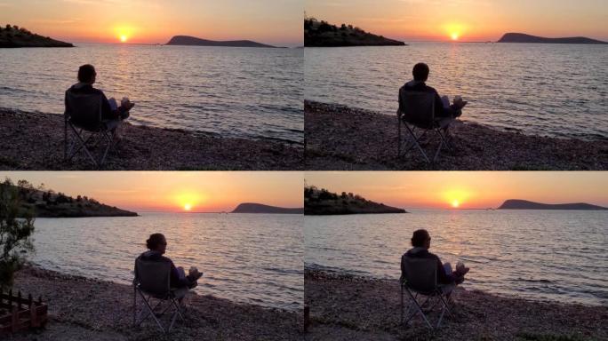 日落时独自坐在海滩上的人