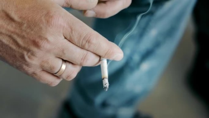 一名男子手里拿着一支吸烟的香烟。不良生活方式和不良习惯。在吸烟者手中抽烟。