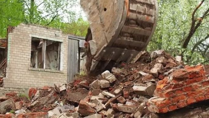 一座老建筑被毁，一辆挖掘机打碎了一座老房子。对象的解构。