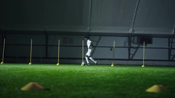 初级非洲足球运动员在大厅训练，用球棒间的球奔跑