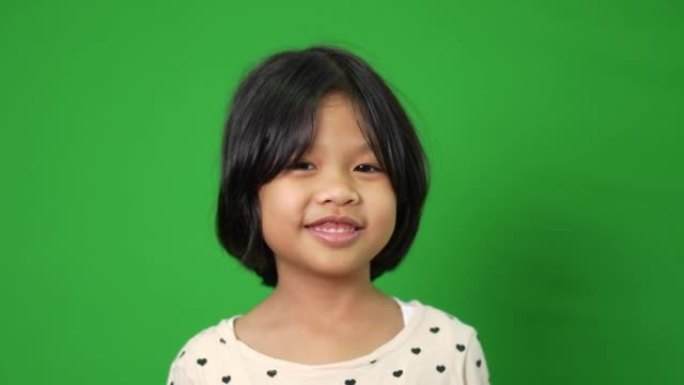 绿色屏幕背景上快乐，微笑和有趣的亚洲儿童女孩的肖像，一个孩子看着相机。学龄前儿童做梦充满能量感觉健康