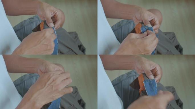 一个男人正在修理破烂的蓝色牛仔裤