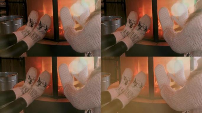 穿着针织袜子和手套的人在壁炉上取暖