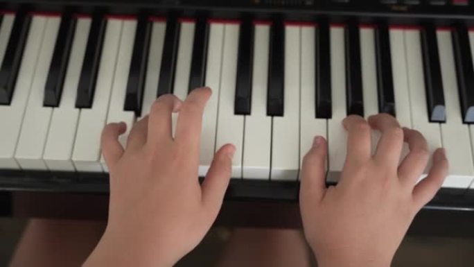 关闭年轻女孩的手在家里用钢琴练习歌曲