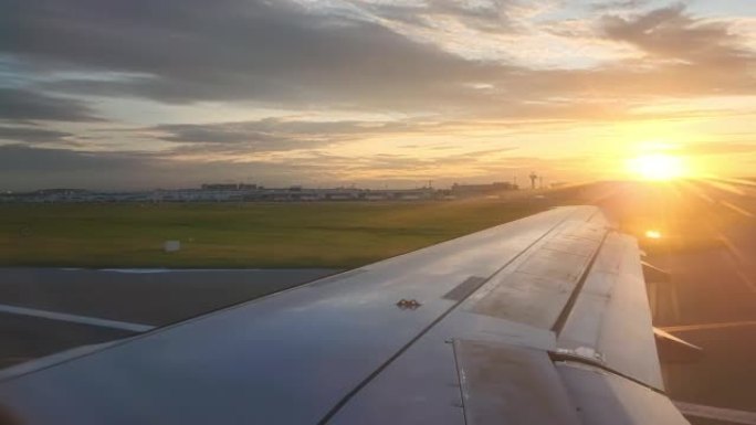透过飞机窗户看日落时橙色的云彩和天空