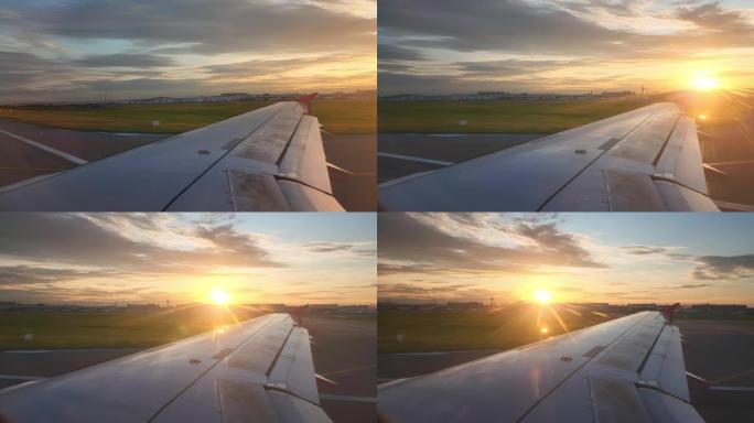 透过飞机窗户看日落时橙色的云彩和天空