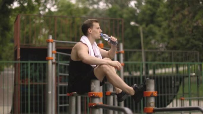 Athletic body shape, guy relax at outdoor gym.