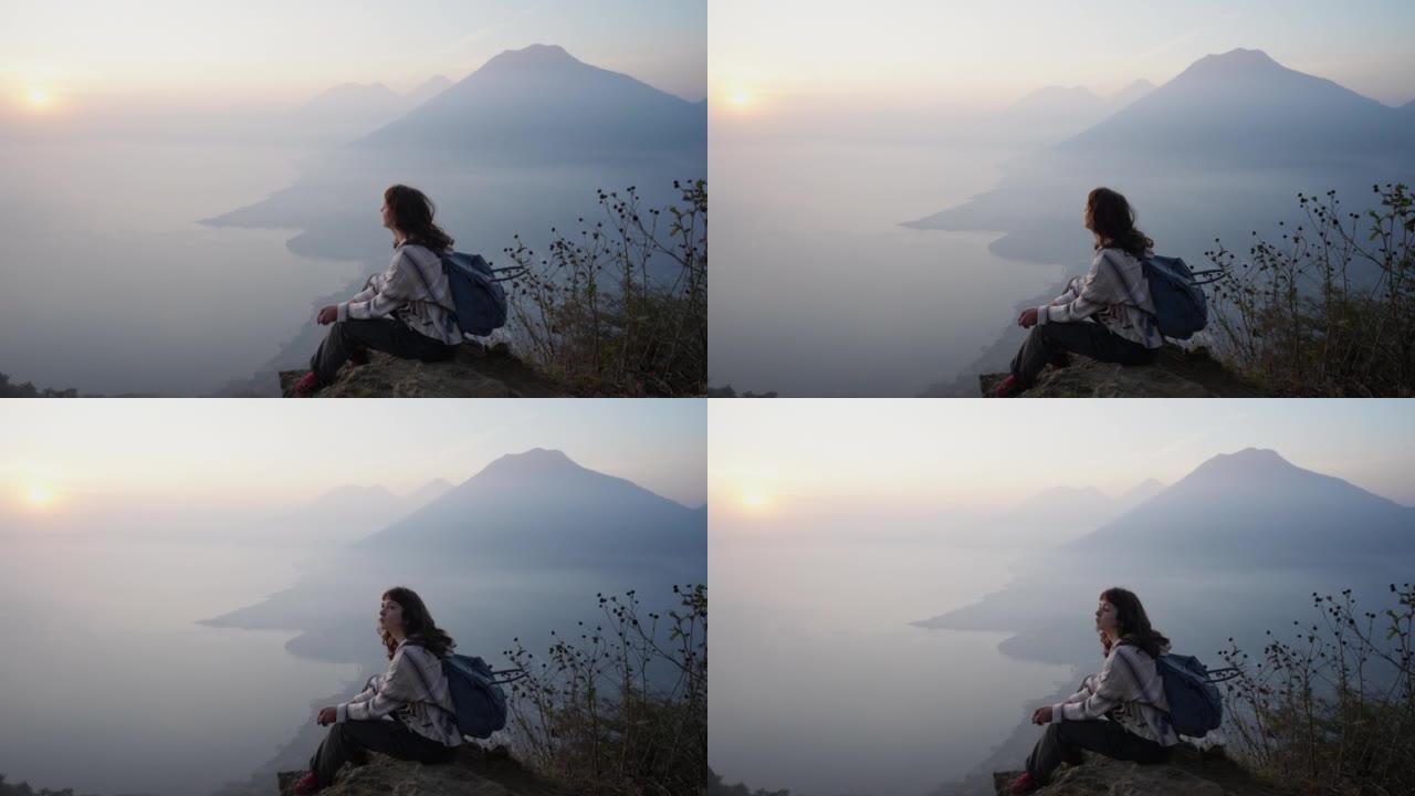 日落时分，坐在危地马拉阿蒂特兰湖背景上的女人