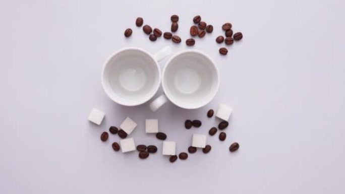 咖啡豆的停止运动动画，带有方糖和灰色背景上的咖啡杯。咖啡店的促销活动。顶视图