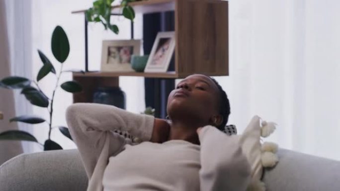 患有颈部疼痛的年轻非洲裔美国妇女在家里的沙发上小睡。一名20多岁的黑人妇女在试图在家休息时颈部疼痛。