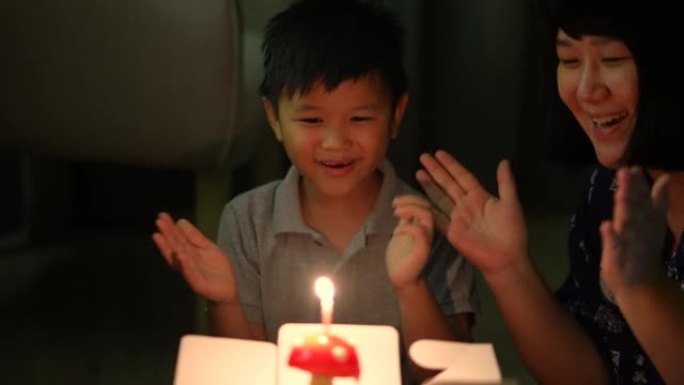 亚洲孩子和他的母亲带着他的生日蛋糕。庆祝和欢乐的概念