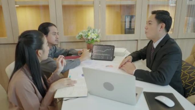 亚洲商业金融同事聚集在办公桌上。两位大三学生向高级财务顾问询问如何阅读股票图表的蜡烛图。笔记本电脑屏