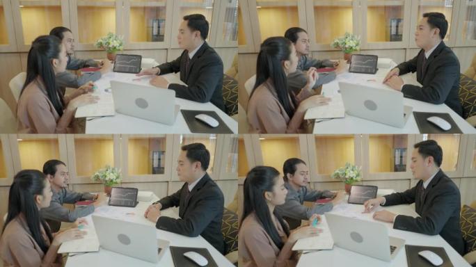 亚洲商业金融同事聚集在办公桌上。两位大三学生向高级财务顾问询问如何阅读股票图表的蜡烛图。笔记本电脑屏