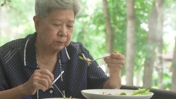 老年妇女在露台上吃饭。成熟的退休生活方式
