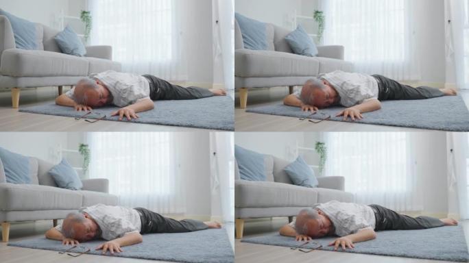 亚洲老年男性在房子里独自行走时摔倒在地上。成熟的老爷爷在家里的客厅退休后做物理治疗后出了事故晕倒。