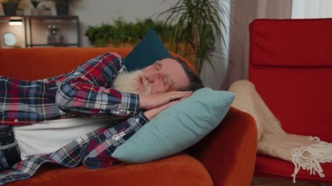 一位疲倦的老人躺在床上休息，在沙发上睡觉