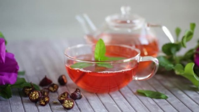 在带有玫瑰果花和薄荷的玻璃茶壶中酿造的玫瑰果茶