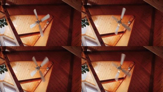 带风扇的吊灯。风扇吊灯在木制天花板上打开。棕色木制天花板，带风扇吊灯旋转