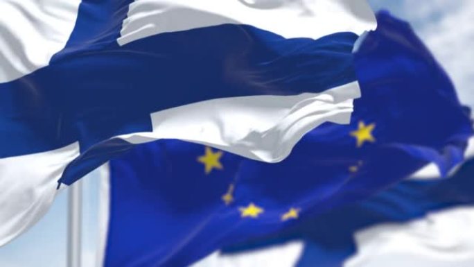 芬兰国旗与模糊的欧盟旗帜在风中飘扬的无缝慢动作循环