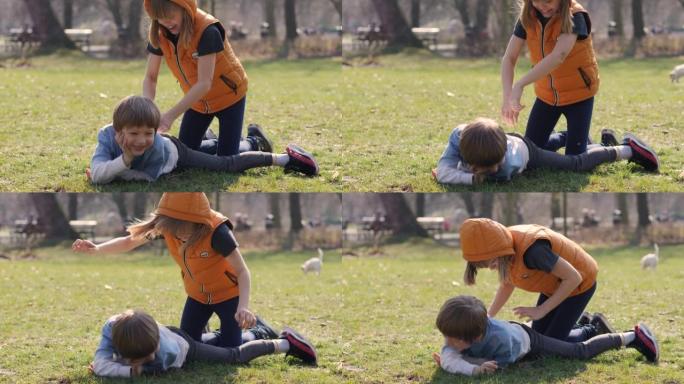 孩子们玩得开心，姐姐女孩在男孩躺在公园草地上给哥哥做按摩